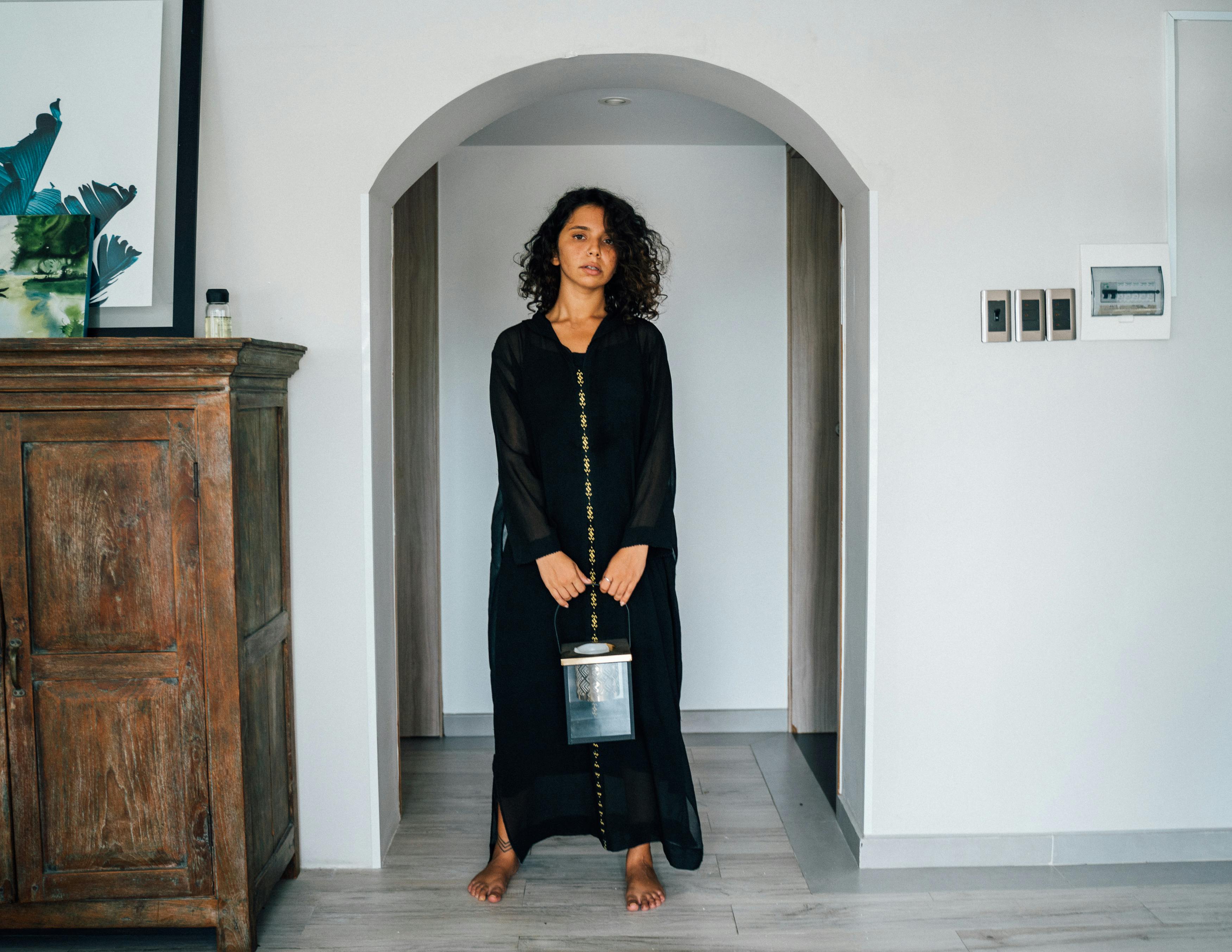 woman in black long sleeve shirt standing beside white wall