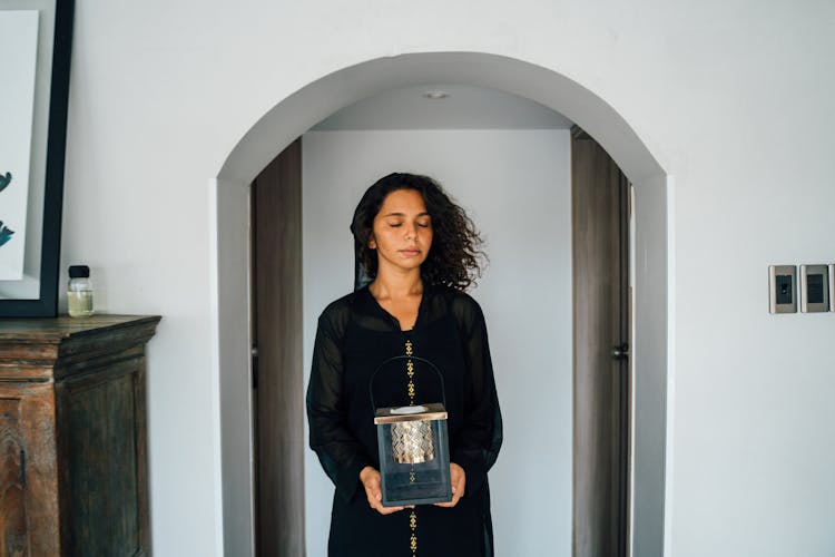 A Woman In Black Top Holding A Lantern