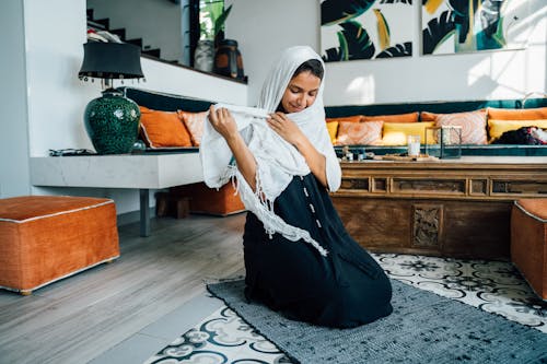 Woman in White Hijab Sitting on Black Area Rug