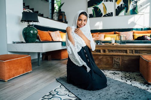 Free Woman in a White Hijab Kneeling on a Prayer Rug  Stock Photo