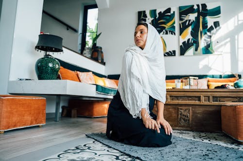 Woman in White Hijab Sitting on Black and White Rug