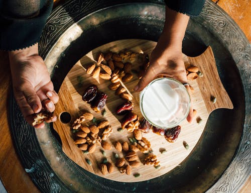 Person Holding a Glass of Milk and Palm Dates