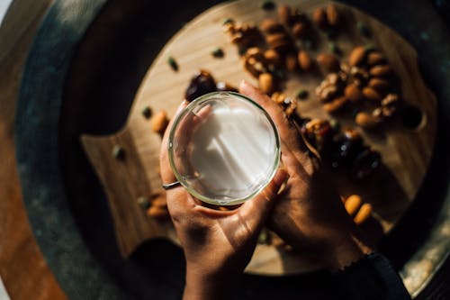 Person Holding a Glass of Milk