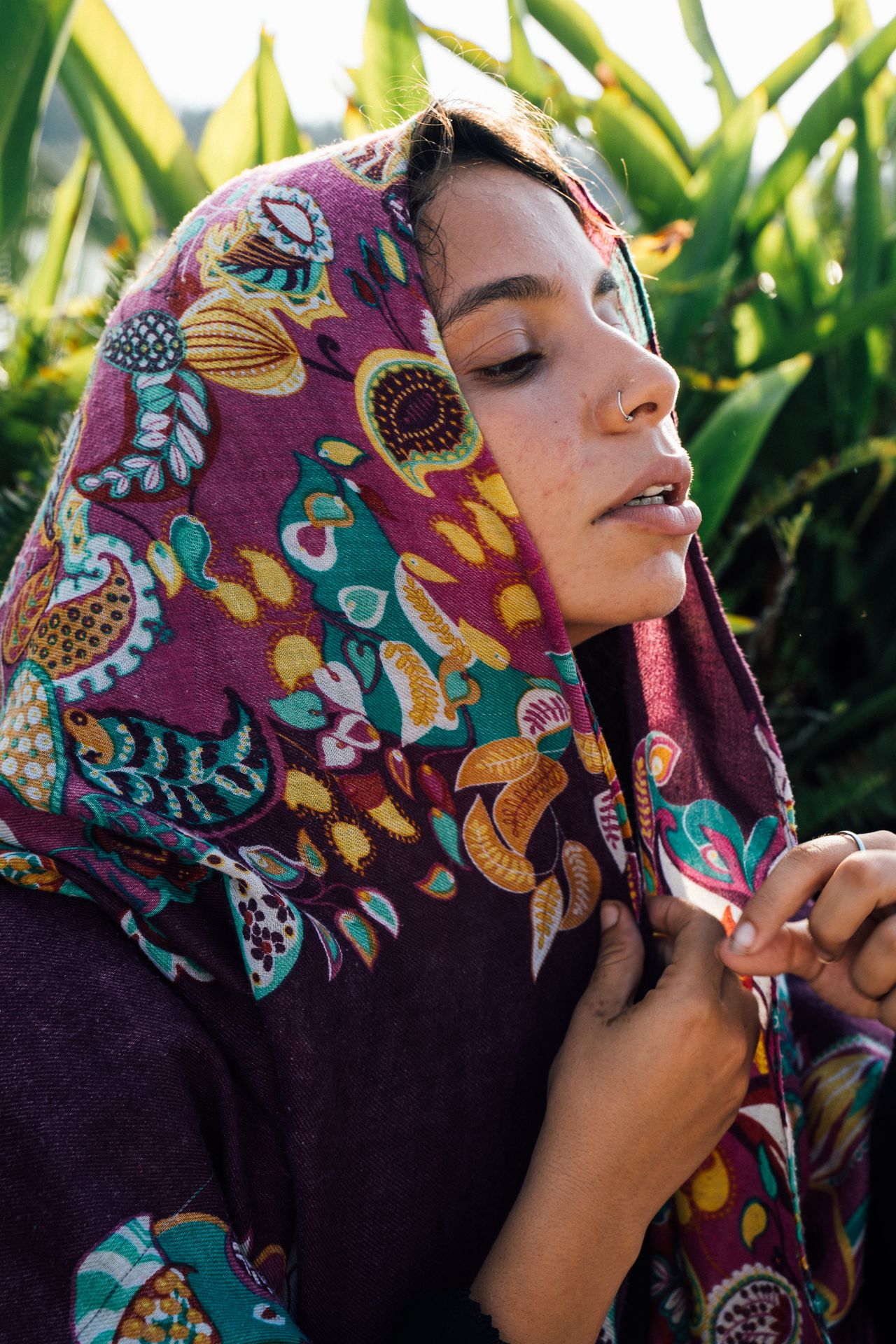 Woman wearing a colourful paisley shawl over her head
