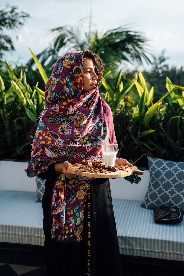 Woman In A Patterned Hijab Holding A Tray With Food And Drink 