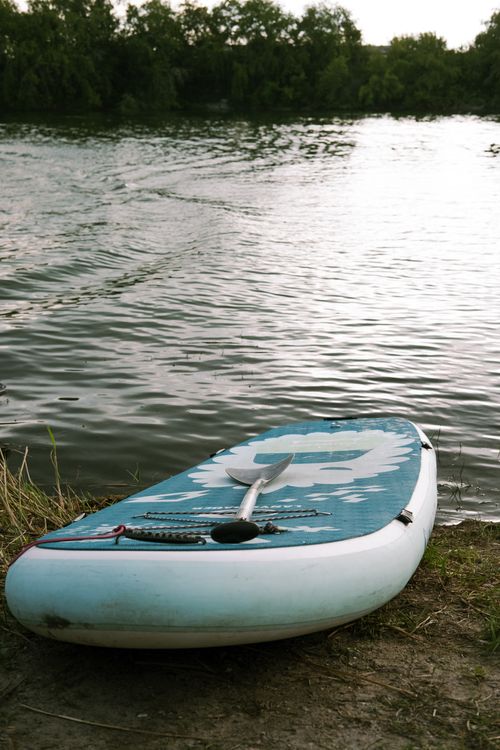Free A kayak rests by a serene lake surrounded by trees in Novosibirsk, Russia, perfect for outdoor recreation. Stock Photo
