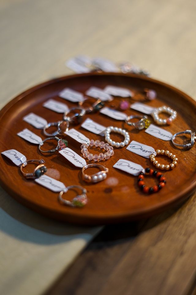 Assorted handmade beaded rings laid out on a wooden tray — photo by Labskiii on Pexels