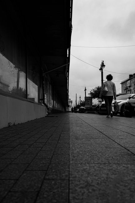 Grayscale urban street scene featuring a woman walking, adding depth and intrigue.