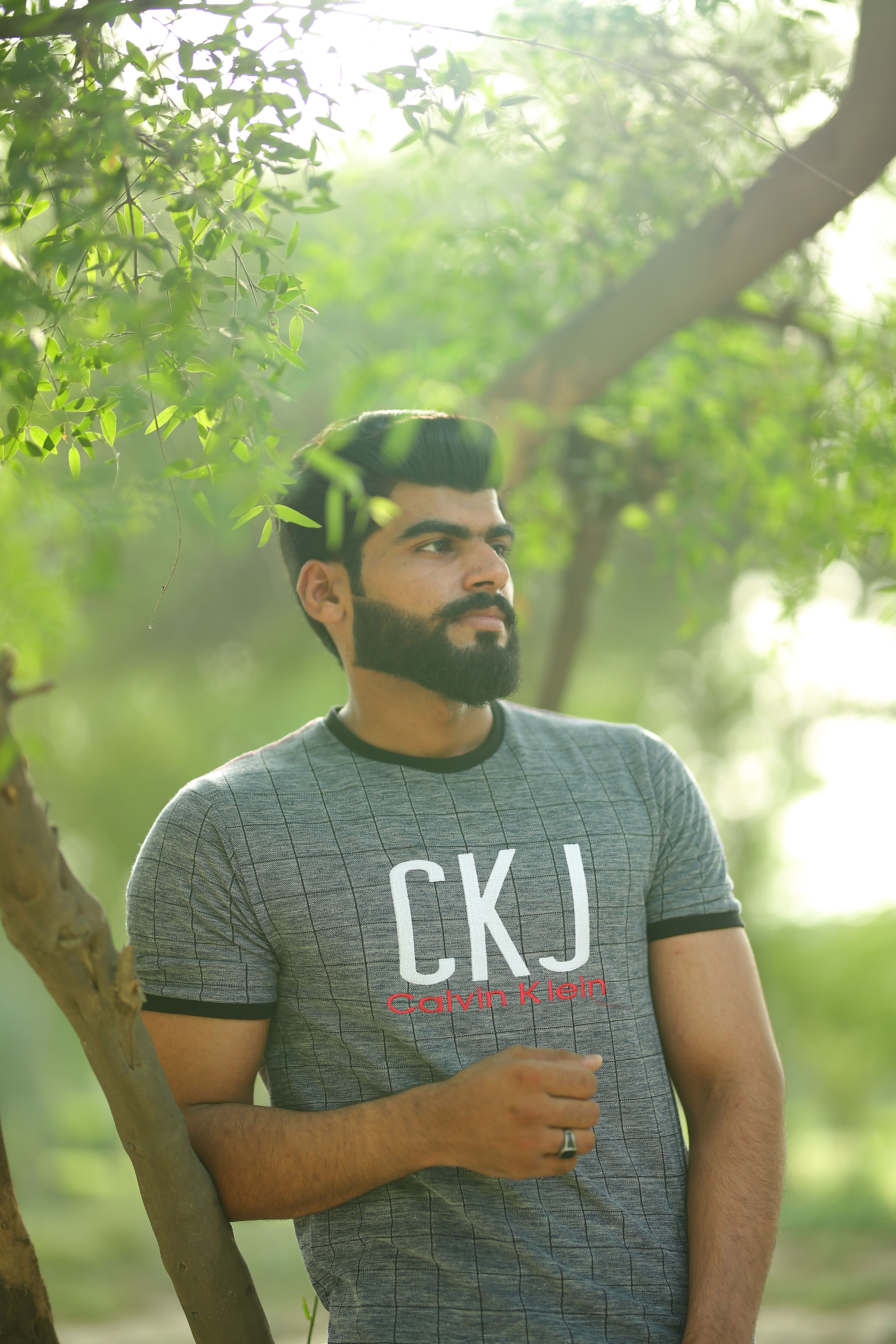 Man with beard and t-shirt standing among trees in Lahore, Pakistan.