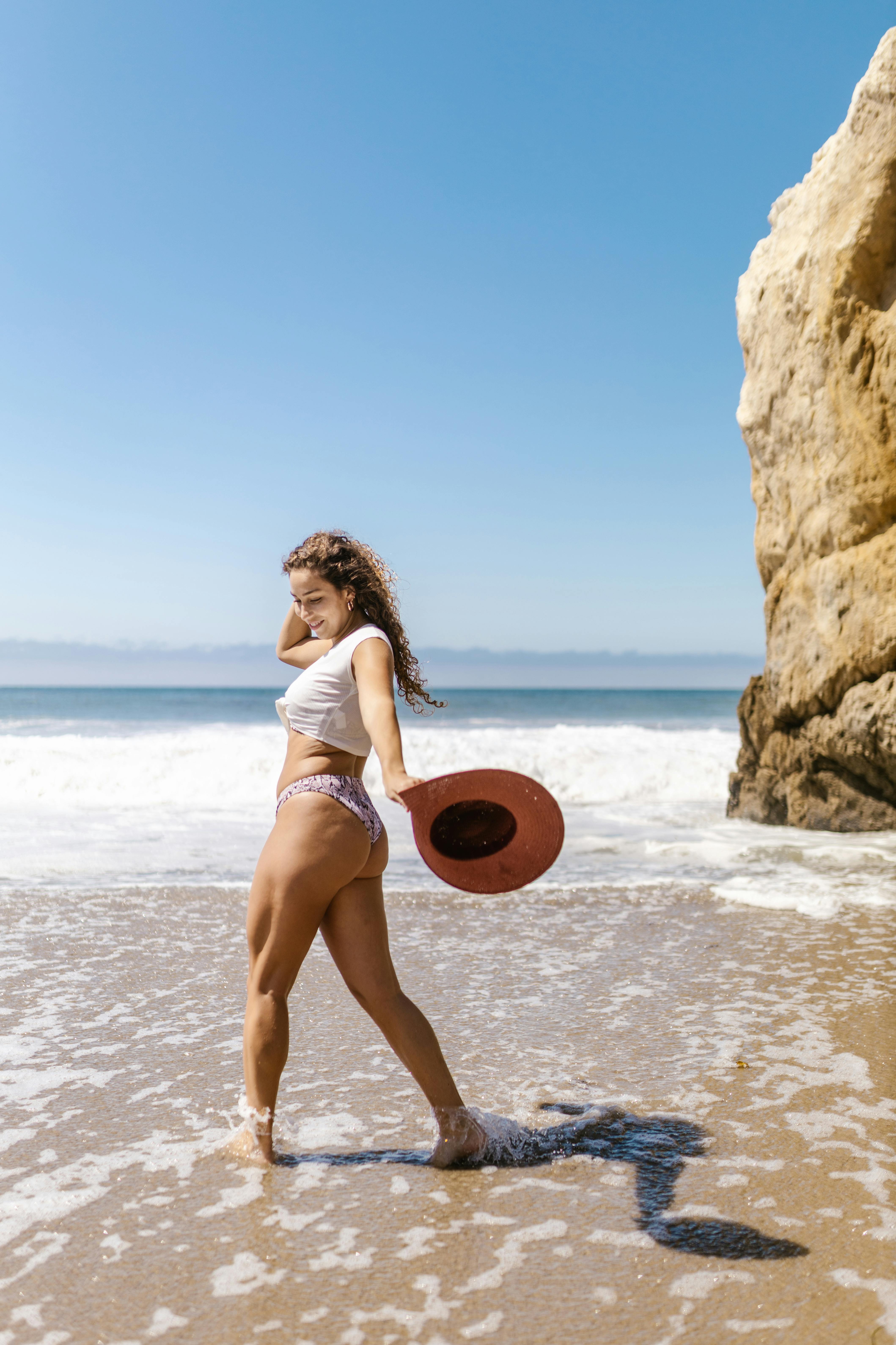 穿着泳衣的无忧无虑的女人在阳光明媚的海滩上享受海风和海浪