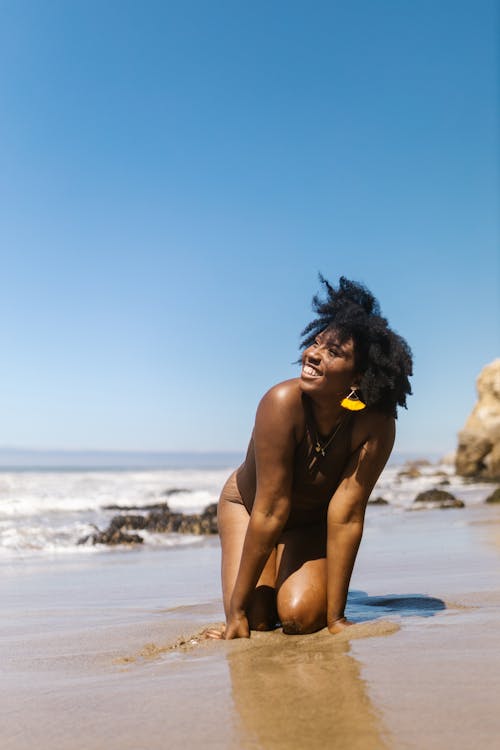 Woman in Brown Swimsuit Kneeling on the Sand