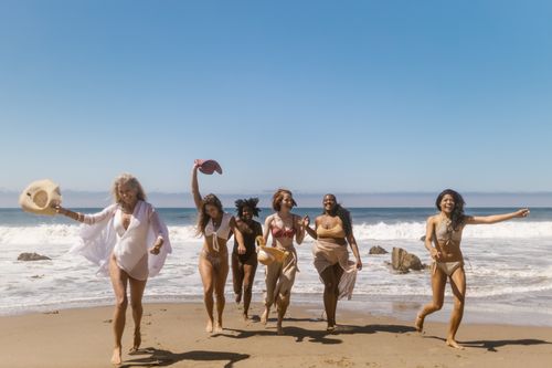 Free Diverse group of women enjoying a sunny beach day, capturing the essence of friendship and happiness. Stock Photo