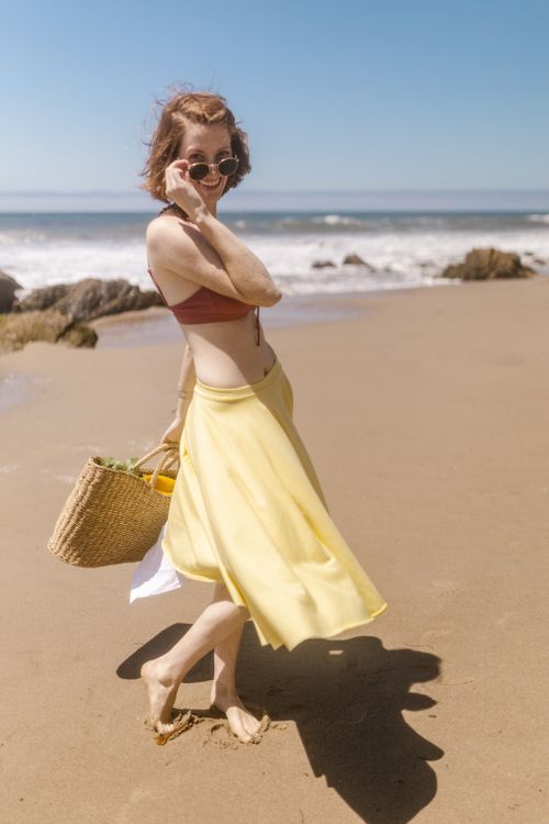 Free A carefree young woman in a skirt and bikini top enjoying a sunny day at the beach. Stock Photo