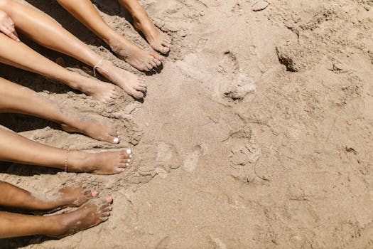 Multiple bare feet on a sandy beach, enjoying a sunny summer day.