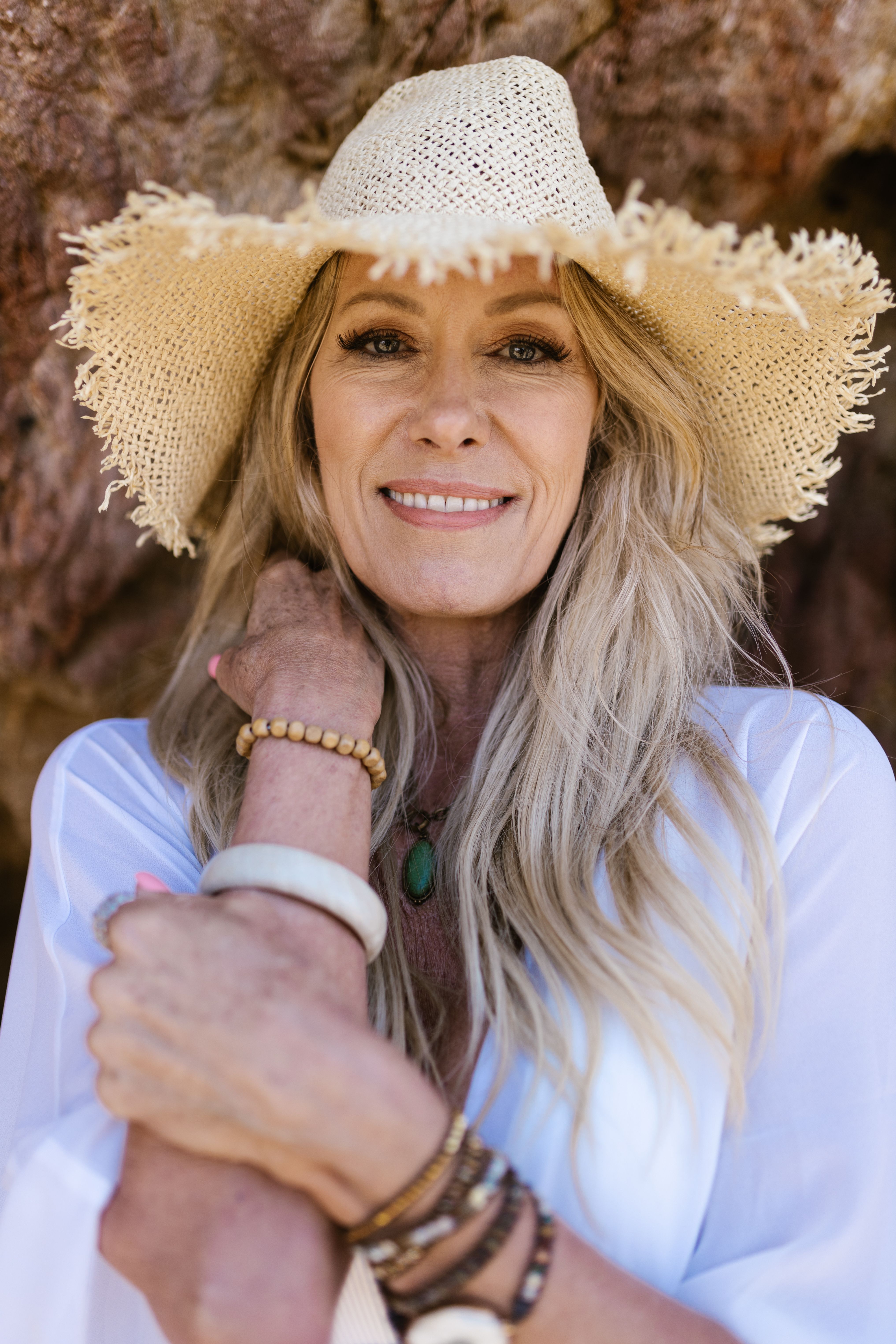 Portrait of a smiling woman in a sun hat, embracing summer vibes outdoors.