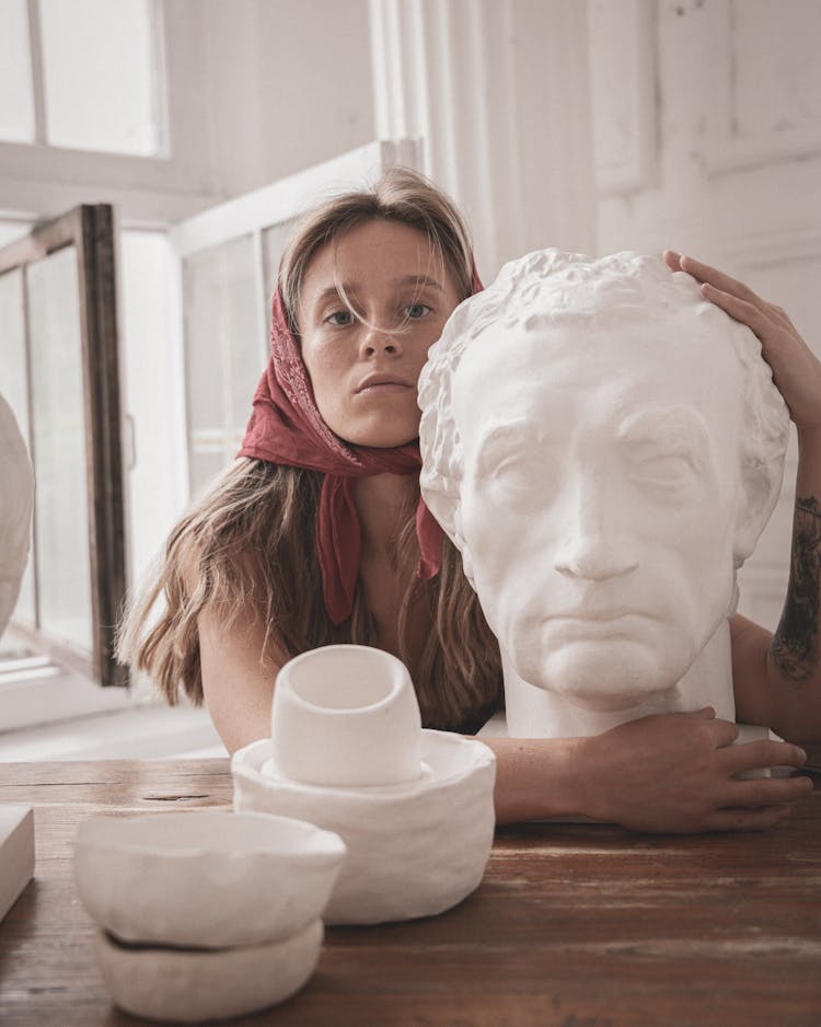 A Woman Hugging A Head Bust Sculpture