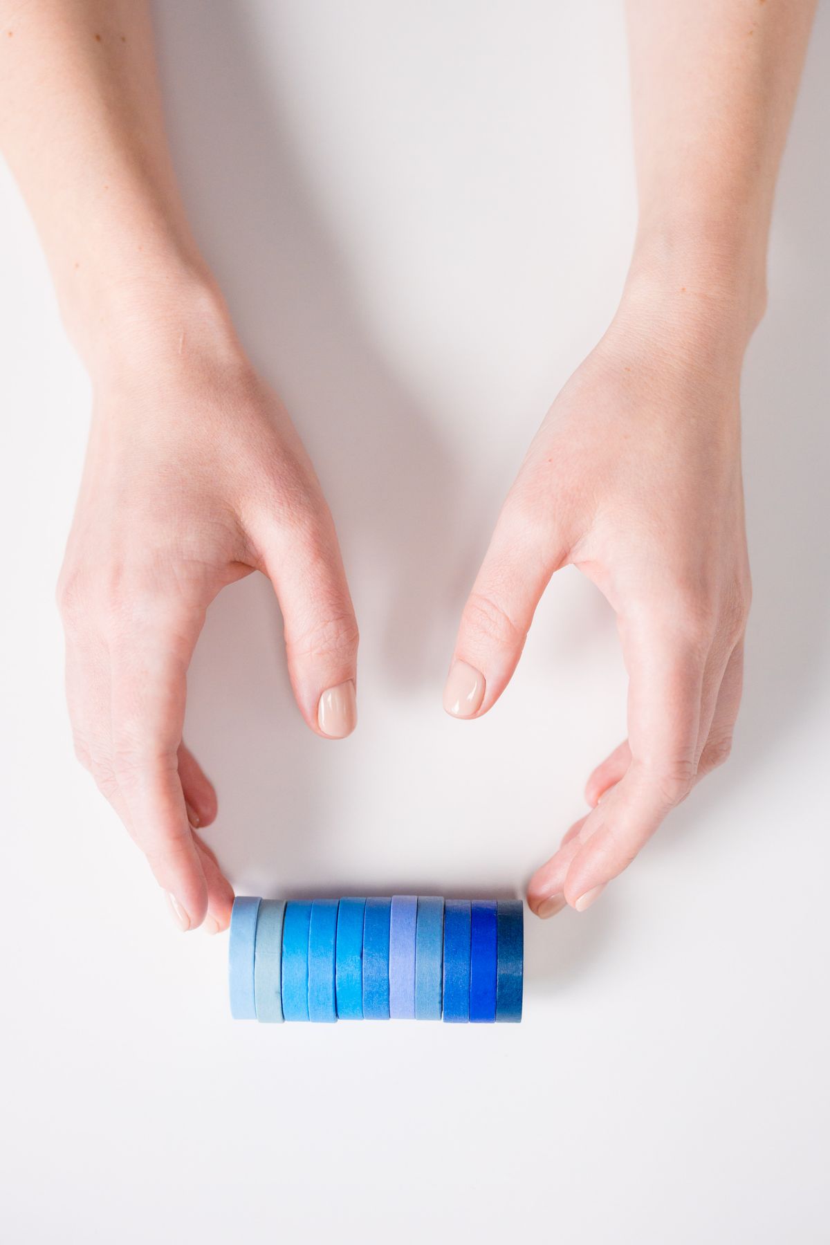 Hands surrounding a gradient arrangement of blue tapes for a water bottle carrier