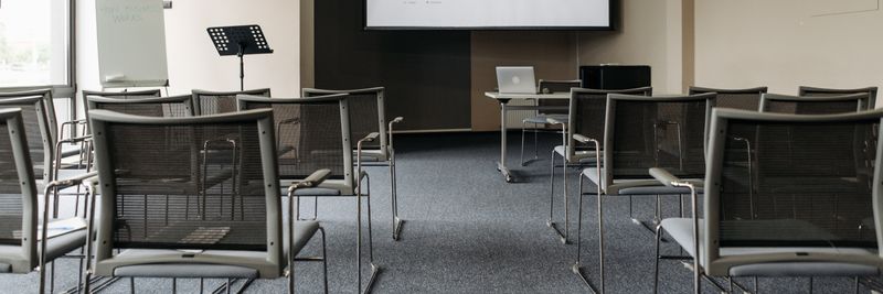 An empty conference room with chairs, a projector screen, and presentation setup.