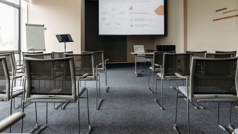 An empty conference room with chairs, a projector screen, and presentation setup.