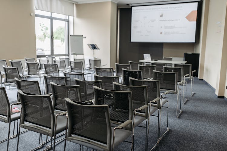 An Empty Chairs And A Screen Projector Inside The Conference Room