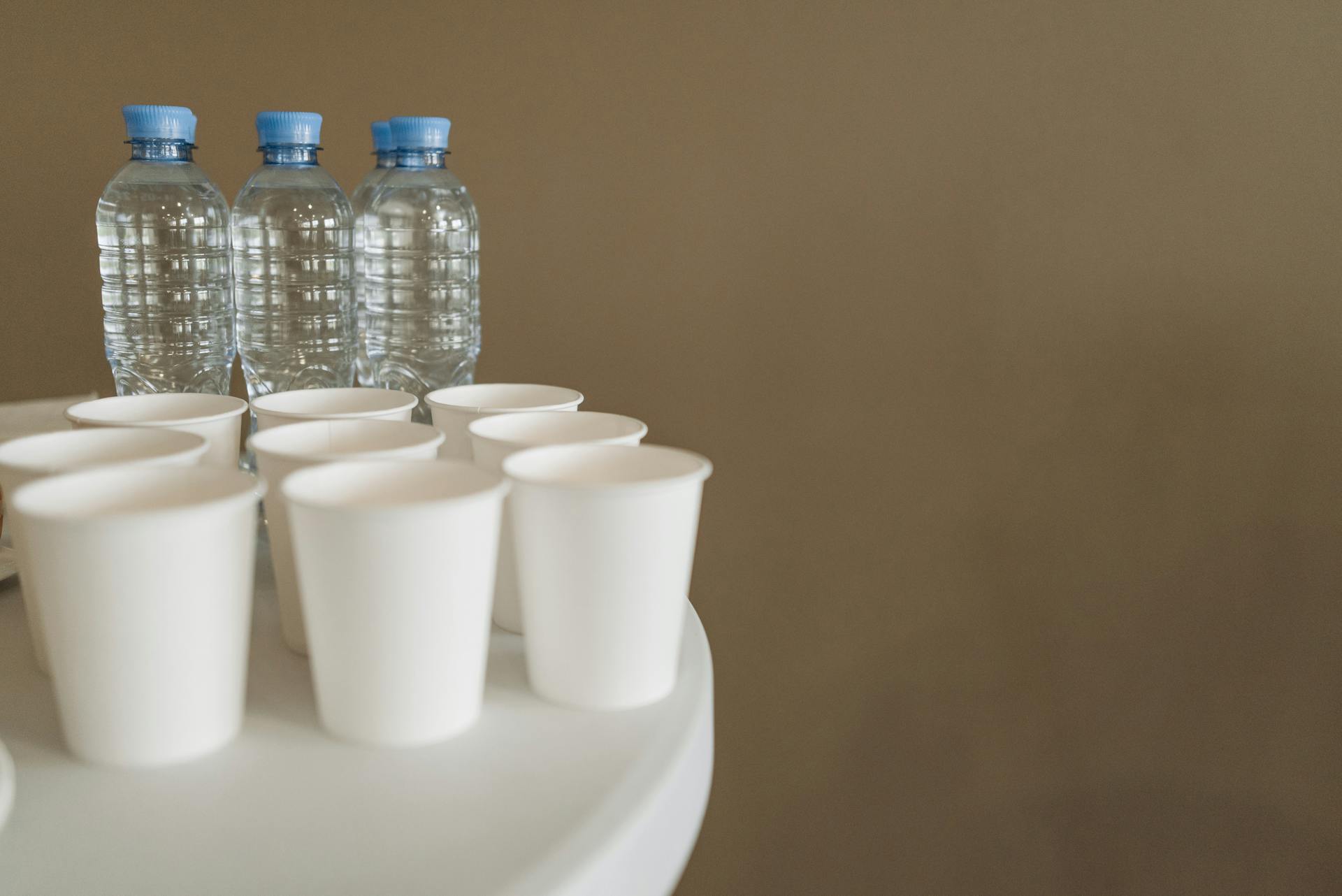 Plastic Bottles of  Water and Cups on Surface