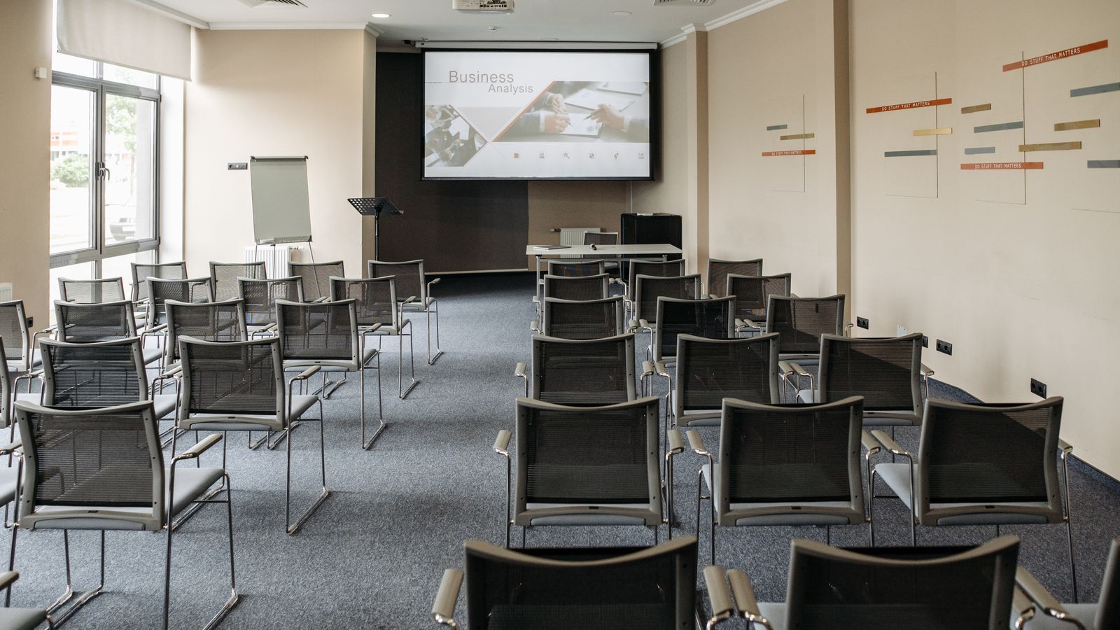 Pusta sala konferencyjna z krzesłami i ekranem przygotowana do wydarzenia firmowego