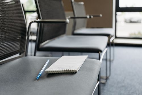 Free Close-up of chairs with a notebook and pen in a well-lit meeting room. Stock Photo