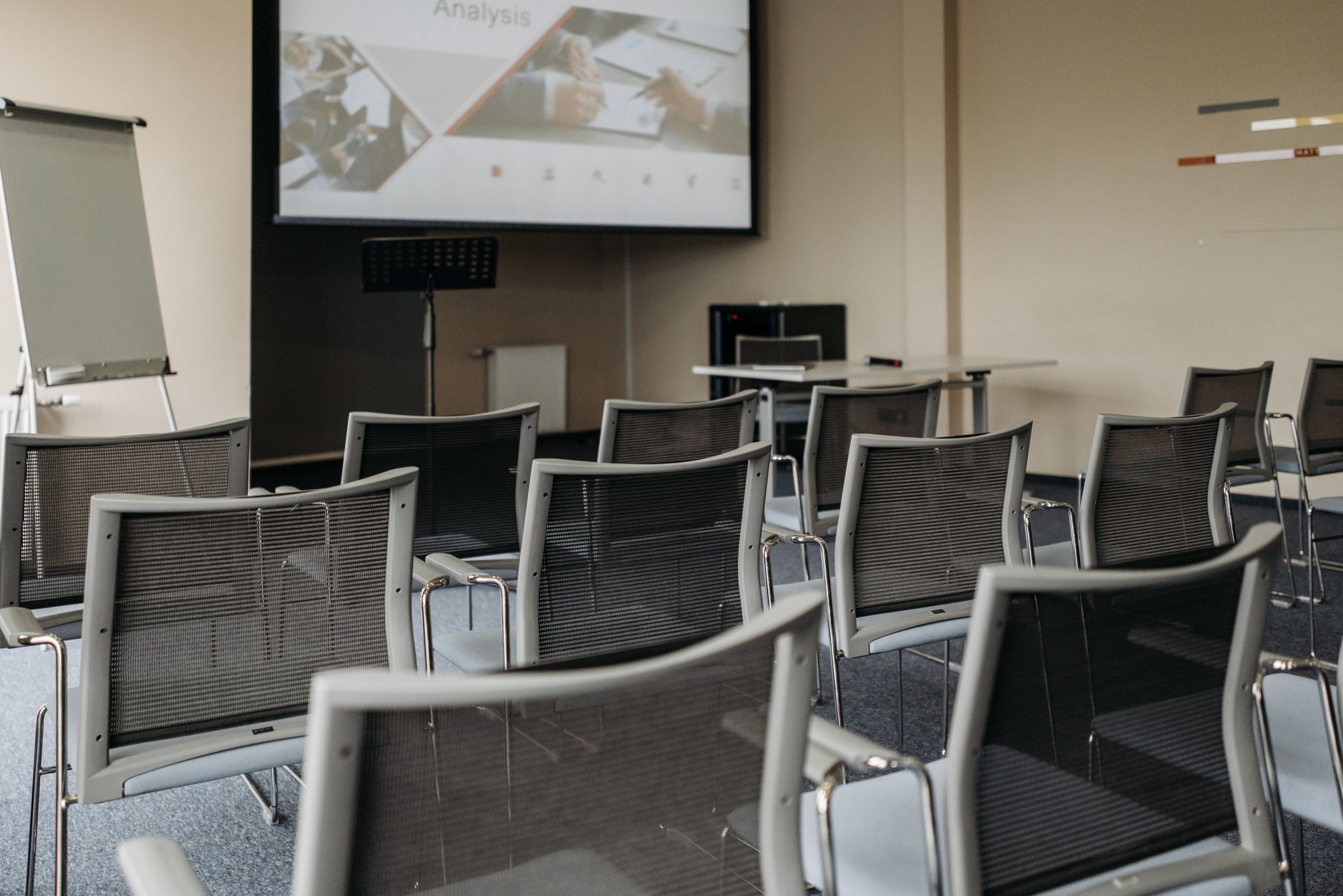 Modern conference room setup with empty chairs, projector screen, and presentation equipment.