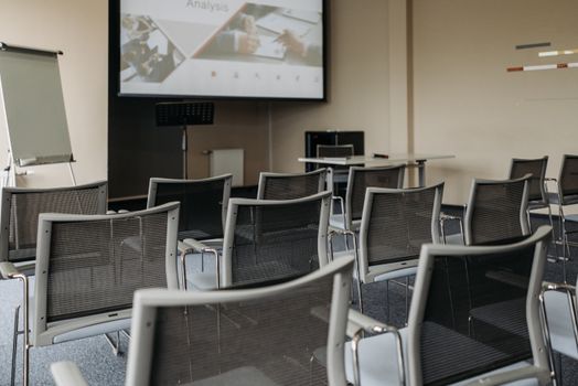Modern conference room setup with empty chairs, projector screen, and presentation equipment.