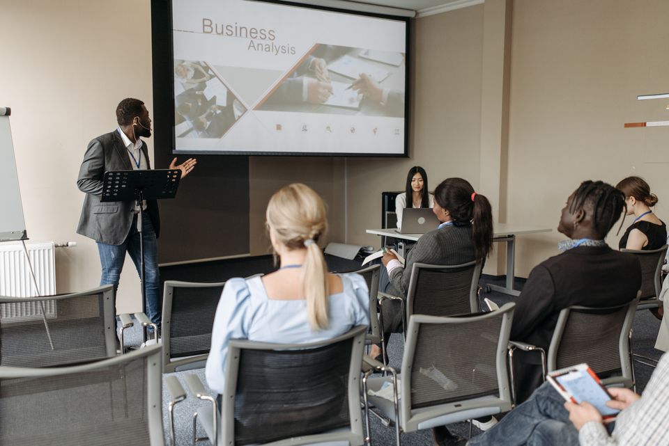A seller workshop in session, presenter at the screen with the room watching — photo by Pavel Danilyuk on Pexels