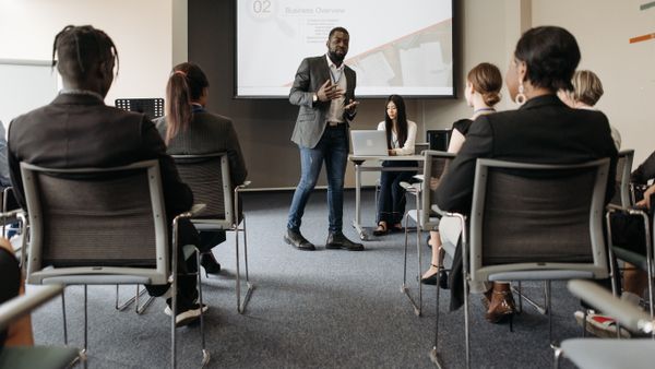 Diverse group attending a business seminar with a presenter and screen display