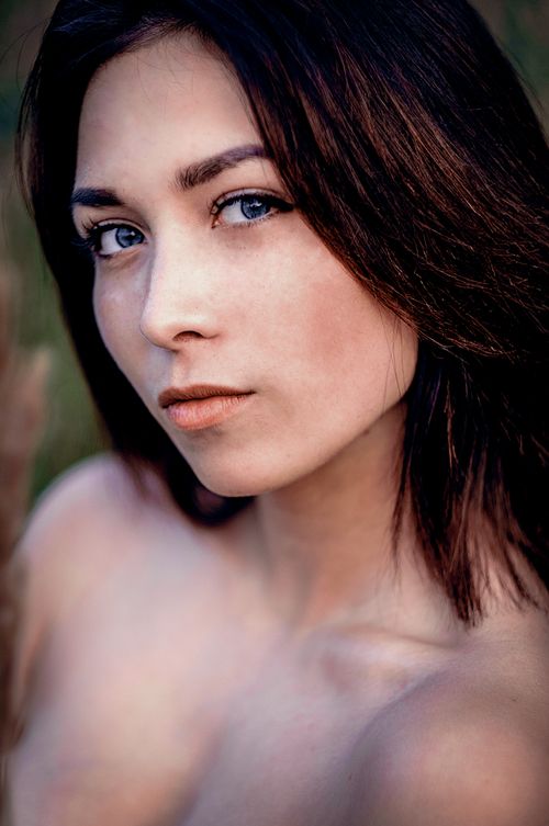 Free Close-up portrait of a young woman with bare shoulders and brunette hair, captured outdoors. Stock Photo