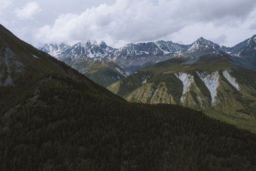 Scenic aerial view of snow-capped Altai Mountains and forested valleys in Russia.