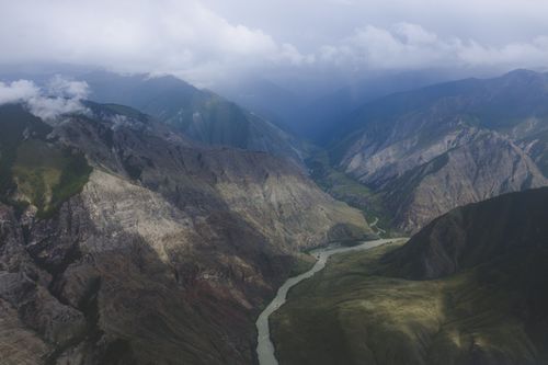 Free Breathtaking aerial photograph showcasing majestic mountains and a winding river under a cloudy sky. Stock Photo