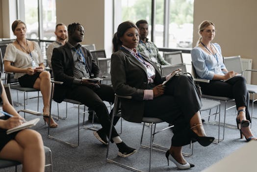 A diverse group of adults attentively listening at a business conference indoors.