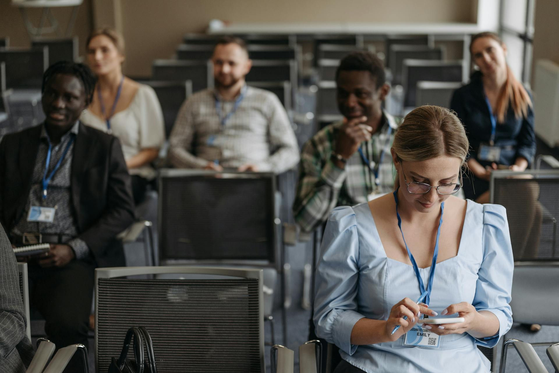 A Woman Using Her Smartphone while at a Business Seminar