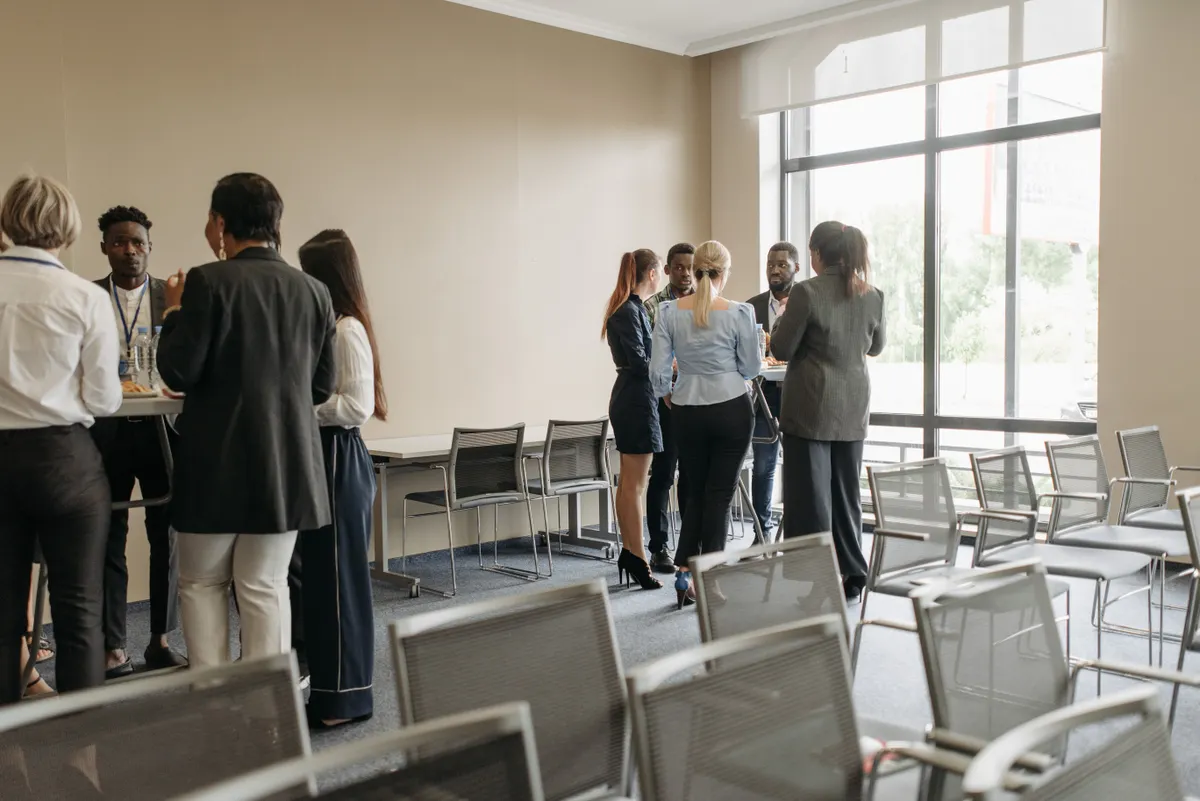 Profesional sedang networking santai di konferensi bisnis menampilkan keragaman tim