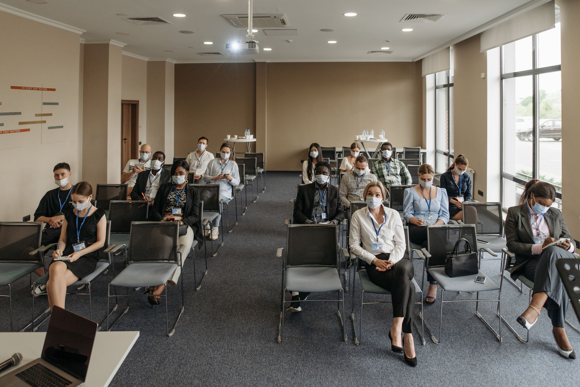 Attendees wearing masks in a socially distanced setup during a business meeting to ensure safety.