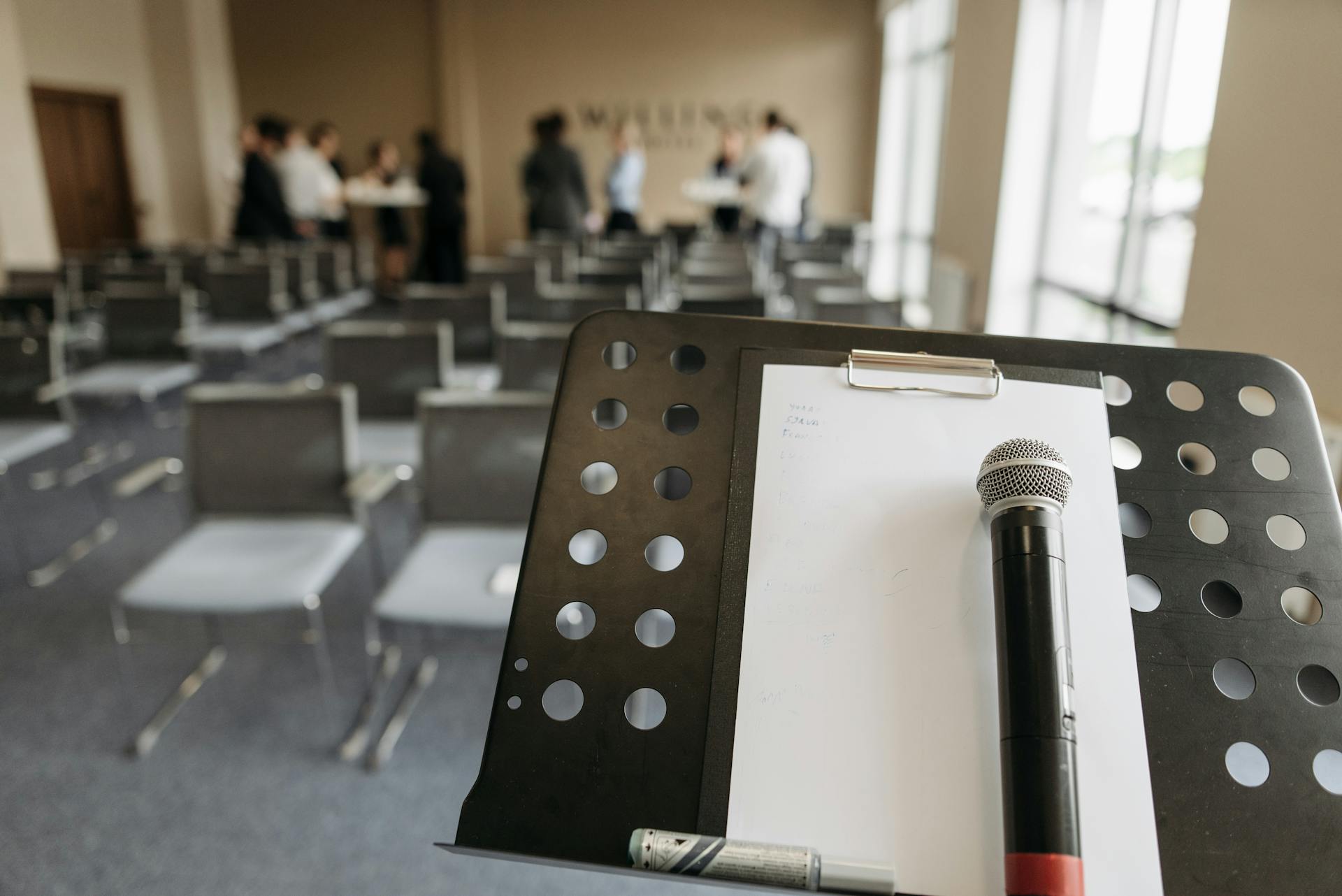 Close-up of a microphone on a stand in a conference room setting.