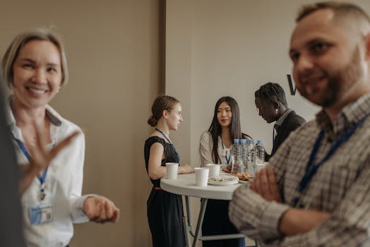A diverse group of adults networking during a business conference break with refreshments.