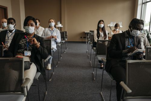 Free Business professionals at a socially distanced conference meeting during the pandemic, all wearing masks. Stock Photo