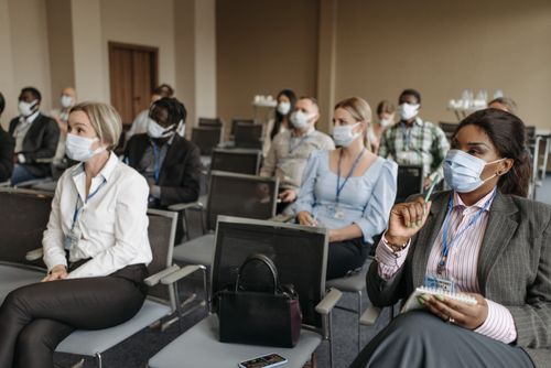 Free Diverse group of professionals in a conference room wearing face masks during a business seminar. Stock Photo