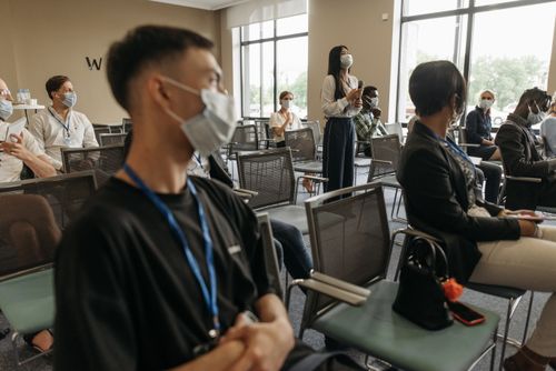 Free A group of diverse adults attending a business seminar while wearing face masks and maintaining social distancing. Stock Photo