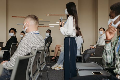 Free A group of diverse individuals in masks attending a business seminar while maintaining social distancing. Stock Photo