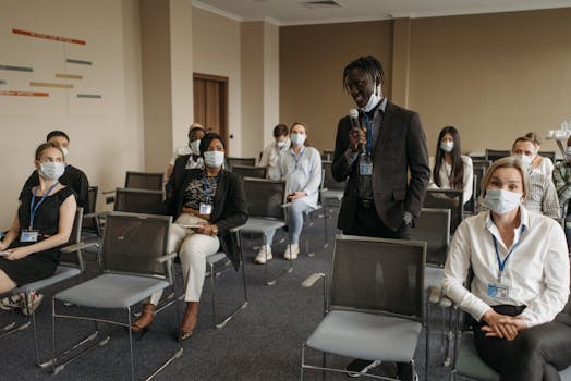Business meeting with diverse participants wearing masks. Pandemic safety protocols in a conference room.