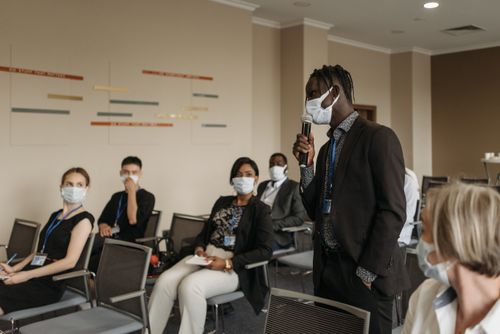 Free Business seminar with participants wearing face masks, actively engaging in a discussion. Stock Photo