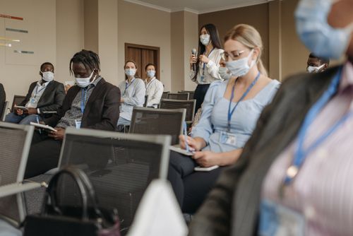 Free Participants wearing masks engage in a business seminar, promoting health and communication. Stock Photo
