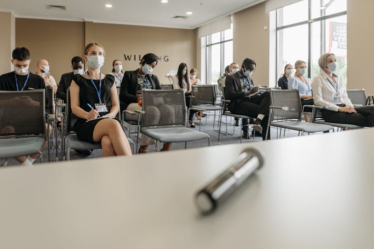 Businesspeople Wearing Face Masks Sitting Inside A Conference Room