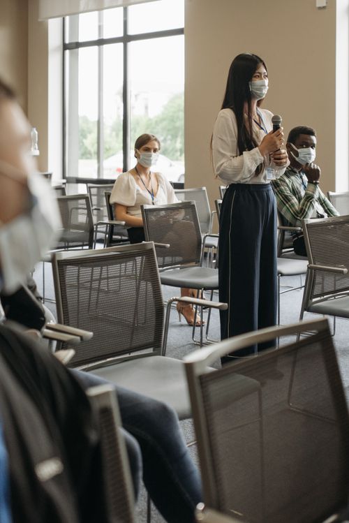 Free Masked participants engage in a business seminar, adapting to post-pandemic norms. Stock Photo