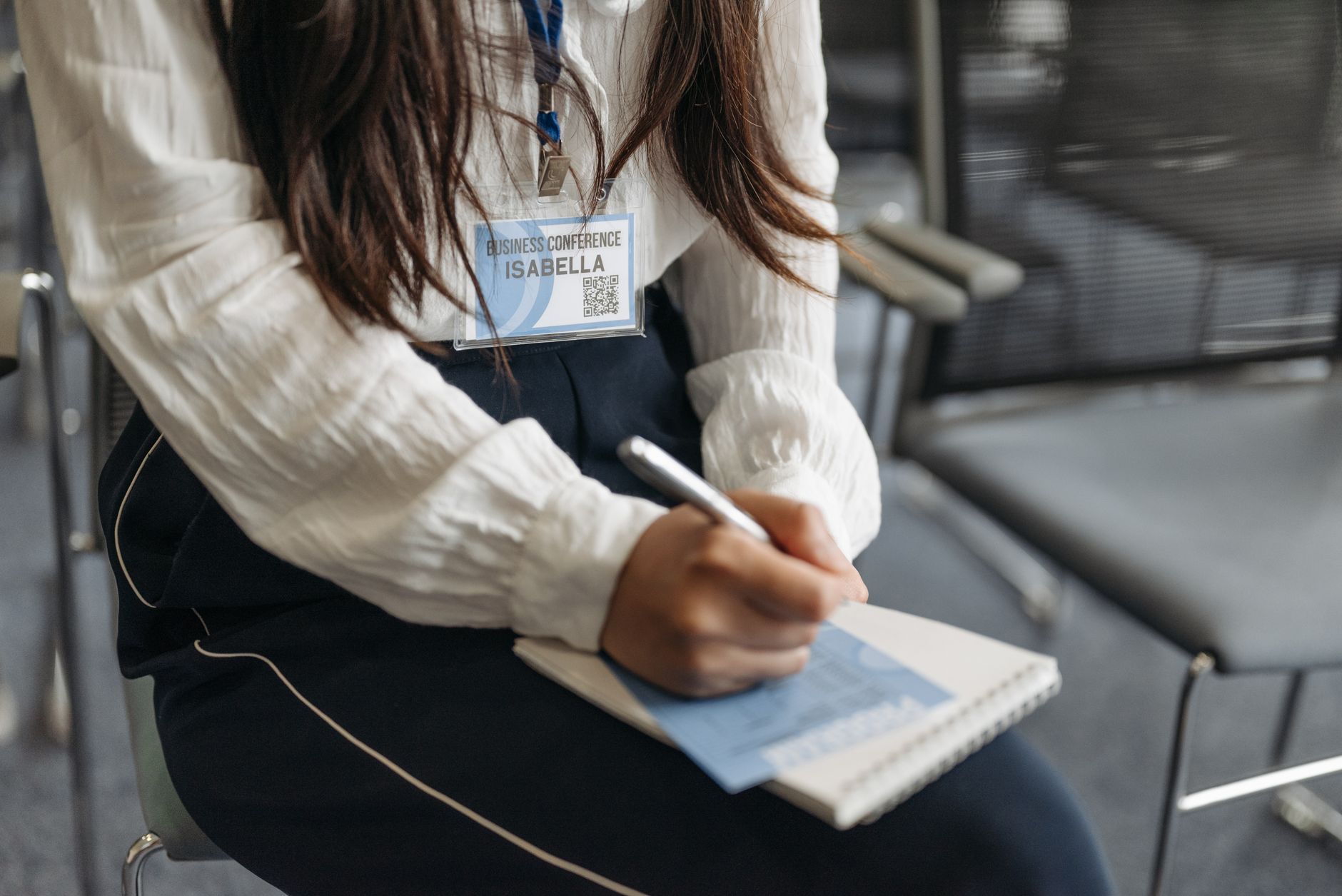 Businesswoman in a white blouse takes notes during a conference.